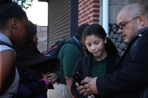  Daniel Ramos, Community Engagement Coordinator, shows students how to submit requests on the Philly311 mobile app.
